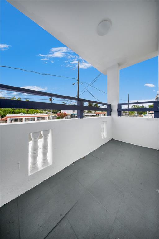 A covered balcony with a gray floor, white walls, and a dark blue metal railing — G4 AVENIDA A, FAJARDO, PR