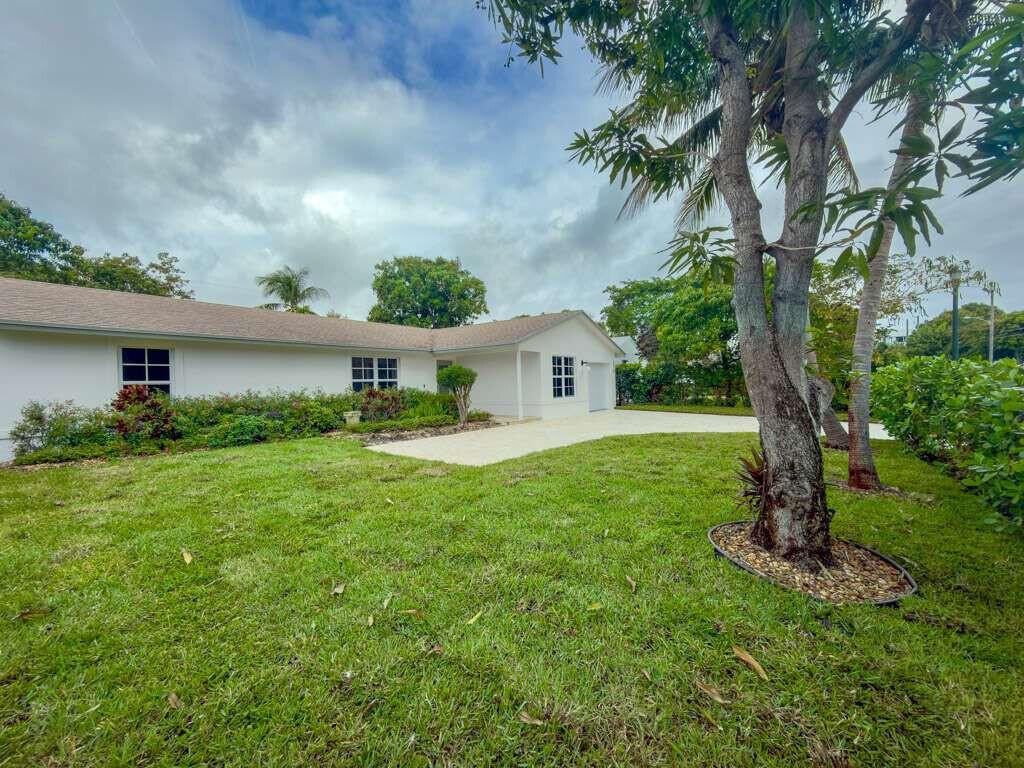 A white single-story house with a paved driveway and a large tree in the yard — 236 SE 3rd Avenue, Delray Beach FL 33483, DELRAY BEACH, FL
