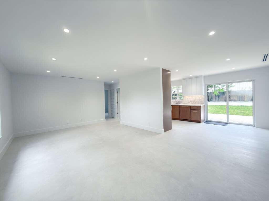 An open-concept living area with light tile floors, recessed lighting, and a view of the kitchen — 236 SE 3rd Avenue, Delray Beach FL 33483, DELRAY BEACH, FL