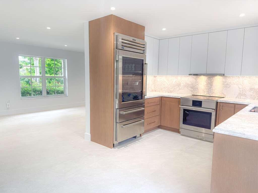 A modern kitchen features light wood cabinetry, stainless steel appliances, and white marble countertops — 236 SE 3rd Avenue, Delray Beach FL 33483, DELRAY BEACH, FL