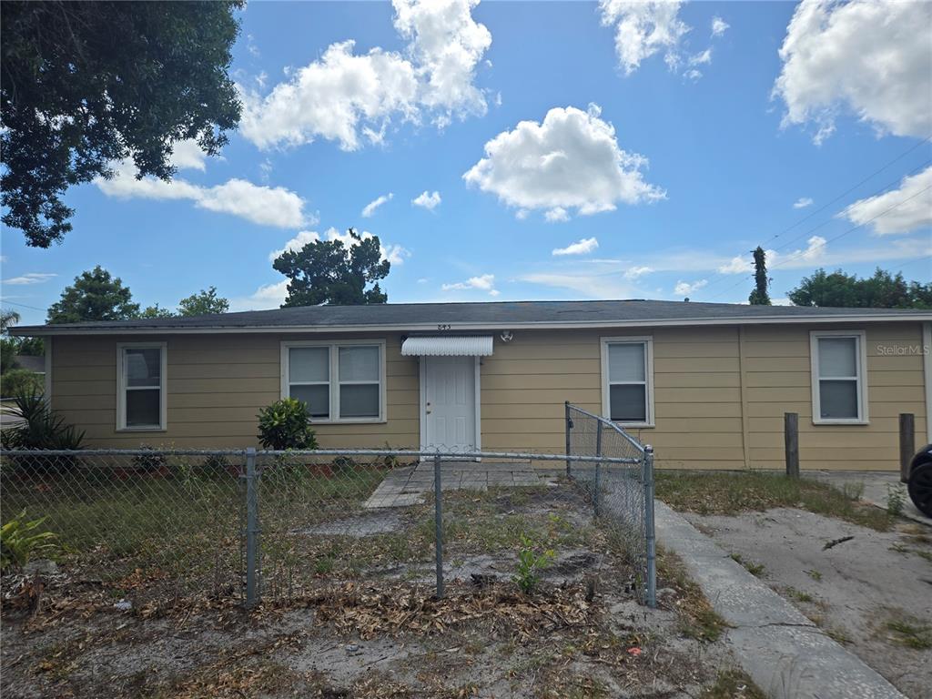 A single-story tan house features a chain-link fence, a front door with an awning, and windows — 843 41ST STREET S, ST PETERSBURG, FL