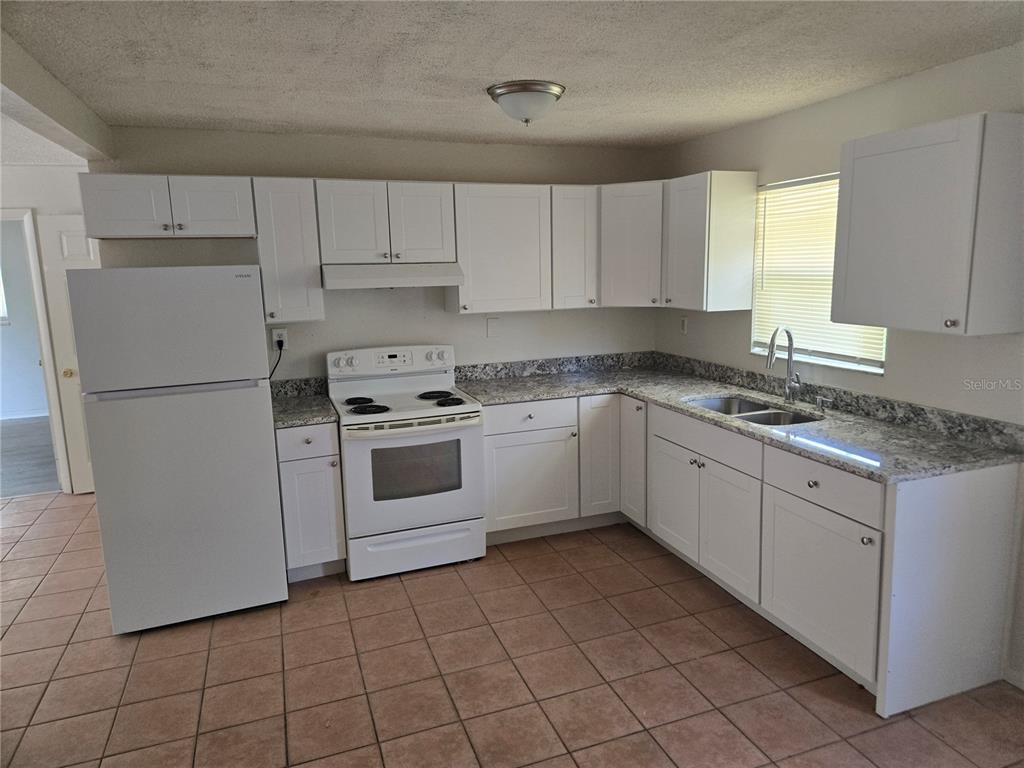 A kitchen with white cabinets, granite countertops, white appliances, and light brown tile flooring — 843 41ST STREET S, ST PETERSBURG, FL