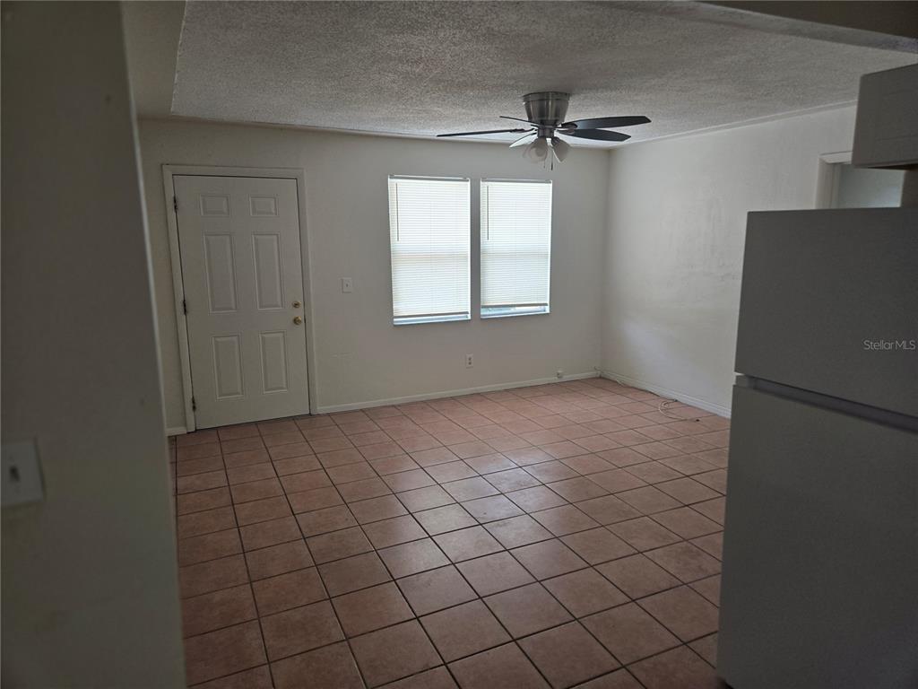 An empty room features beige tile flooring, white walls, two windows, and a ceiling fan — 843 41ST STREET S, ST PETERSBURG, FL