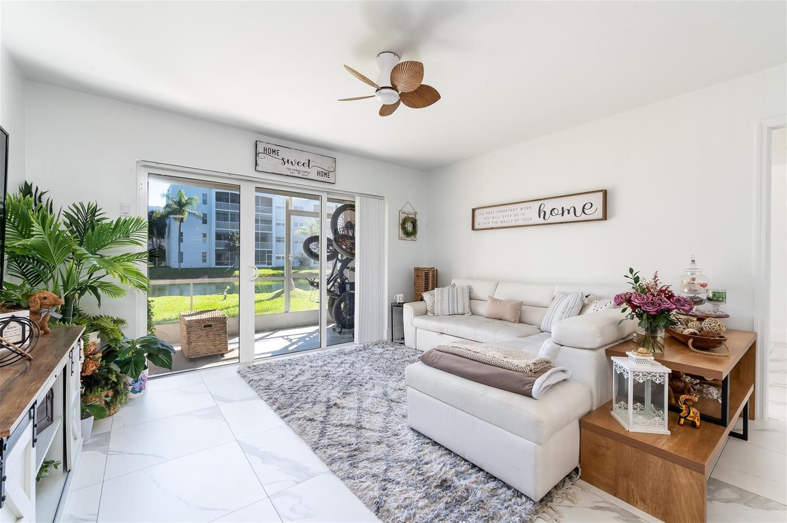 A bright living room features white tile floors, a sectional sofa, and a sliding glass door — 600 NE 2nd Street # 105, Dania Beach FL 33004, DANIA BEACH, FL