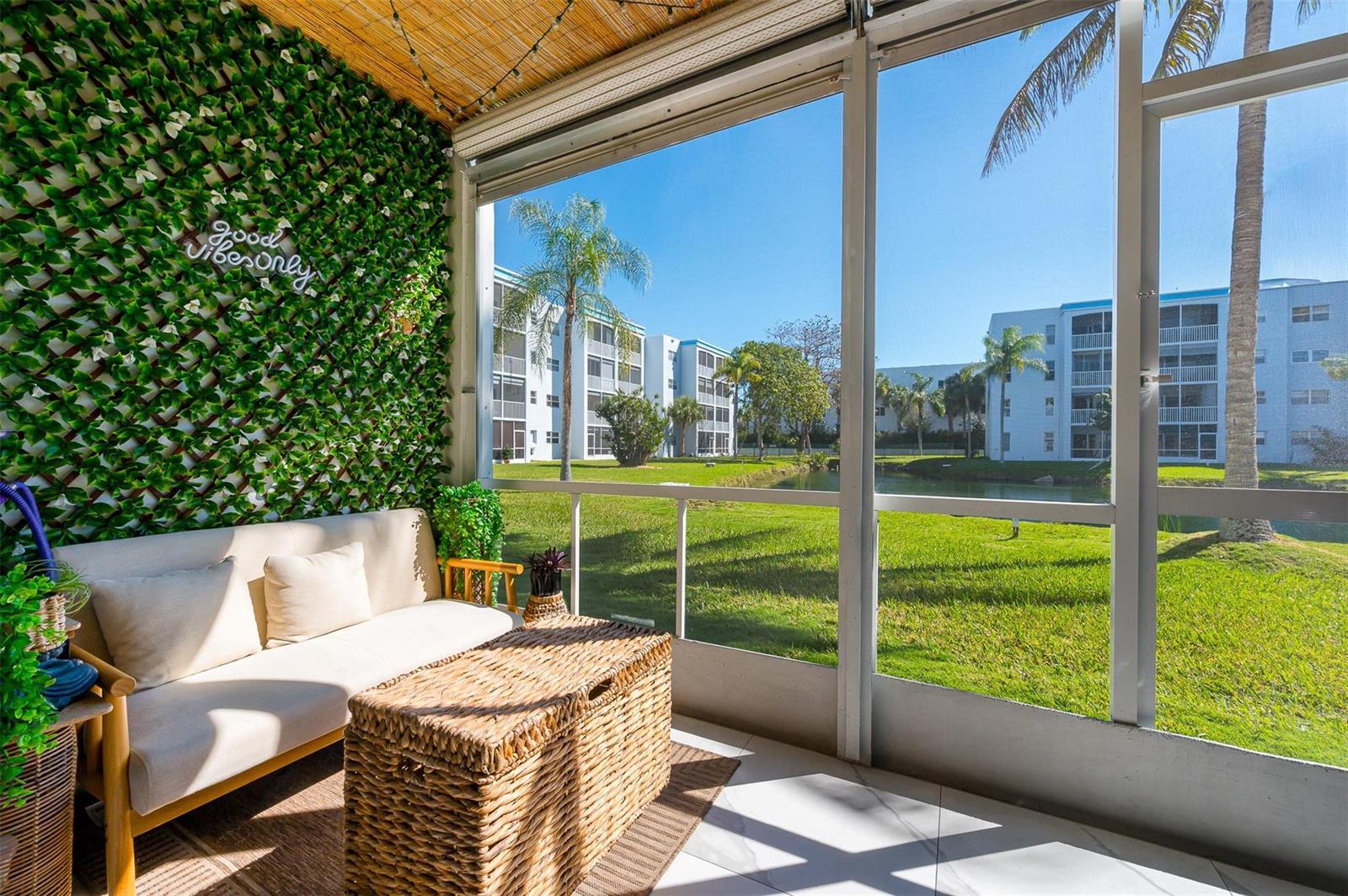 A screened-in patio features a sofa, wicker storage trunk, and a green wall with signage — 600 NE 2nd Street # 105, Dania Beach FL 33004, DANIA BEACH, FL