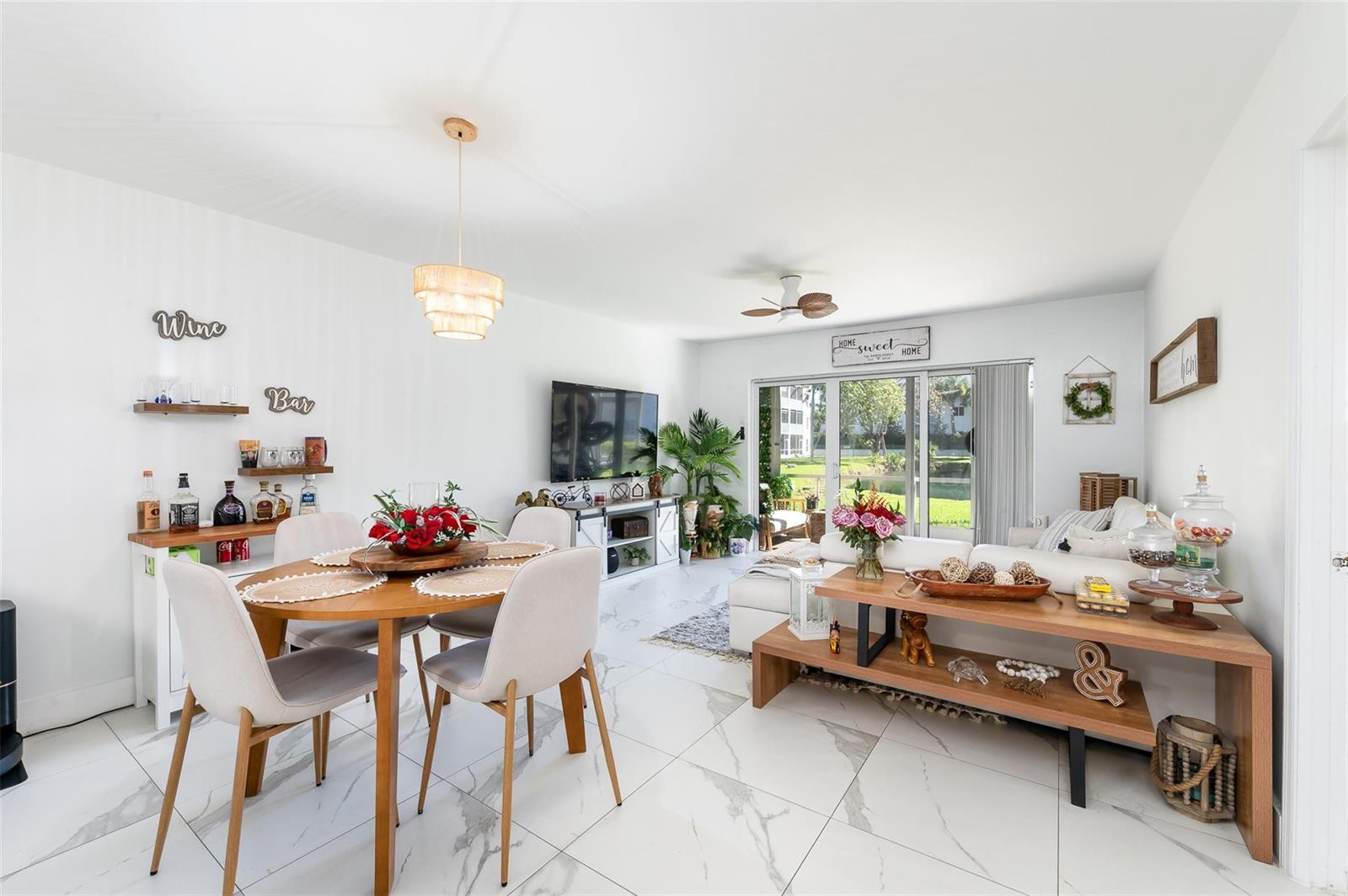 An open-concept living and dining area features white marble-look tile flooring and a sliding glass door — 600 NE 2nd Street # 105, Dania Beach FL 33004, DANIA BEACH, FL