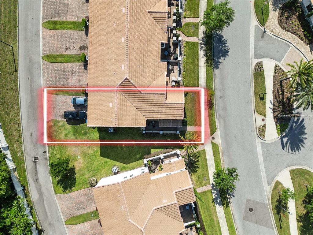 An aerial view shows a townhome with a driveway, a red outline, and surrounding landscaping — 129 KENNY BOULEVARD, HAINES CITY, FL