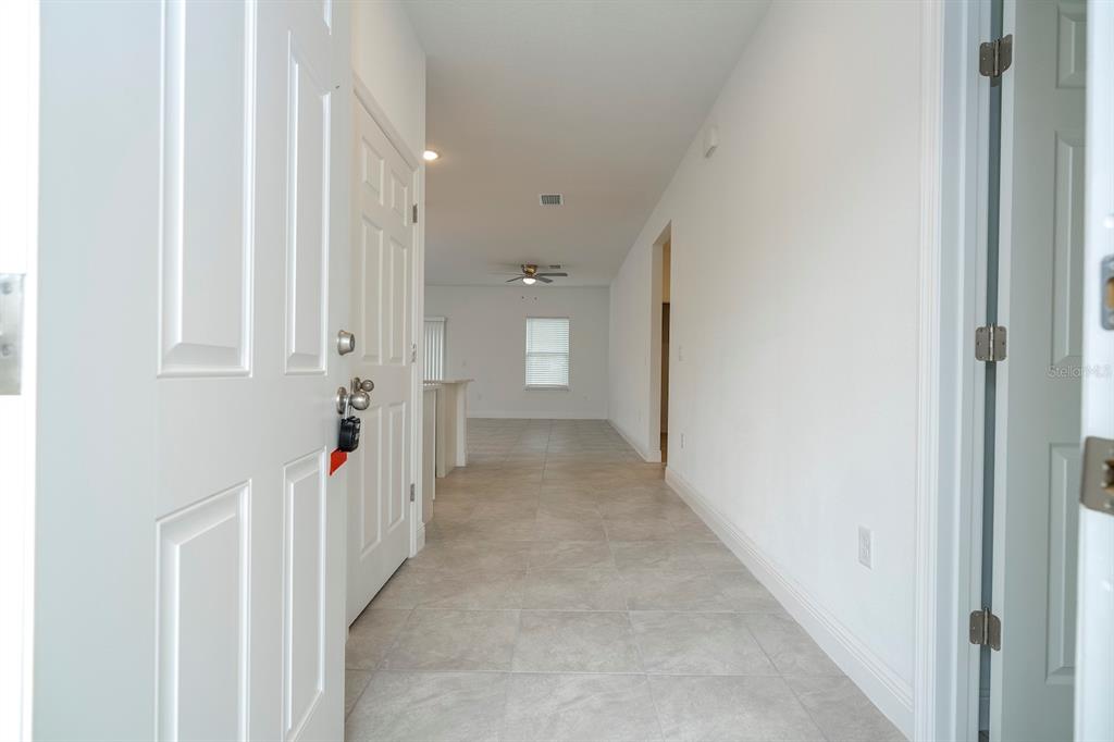 A view from an open doorway looking down a tiled hallway into an open living area — 7811 N DARBY DRIVE, DUNNELLON, FL