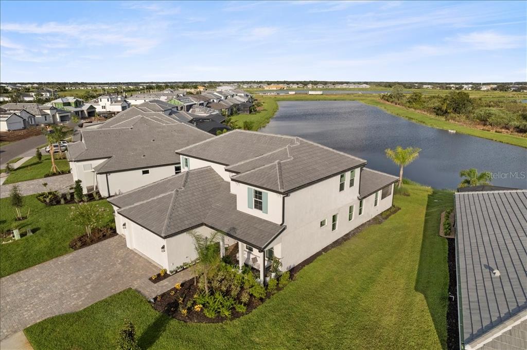 An aerial view shows a two-story white house with a gray tile roof near a pond — 17703 SAVORY MIST CIRCLE, LAKEWOOD RANCH, FL