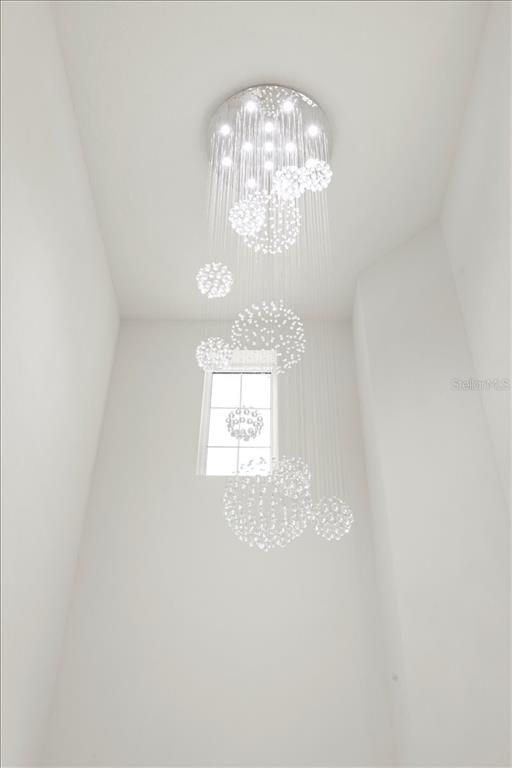 A modern crystal chandelier hangs in a tall, white-walled foyer with a single window — 17703 SAVORY MIST CIRCLE, LAKEWOOD RANCH, FL