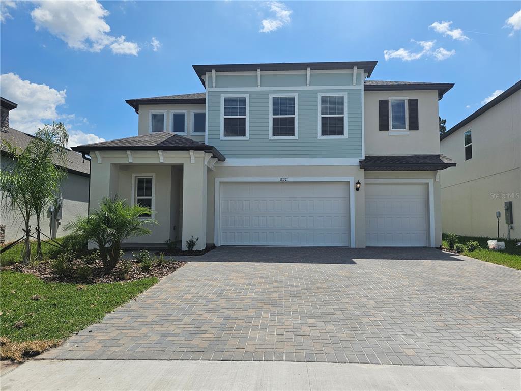 A two-story house features a light-colored stucco exterior, blue siding accents, and a paved driveway — 18271 PEARL VIEW PLACE, LUTZ, FL