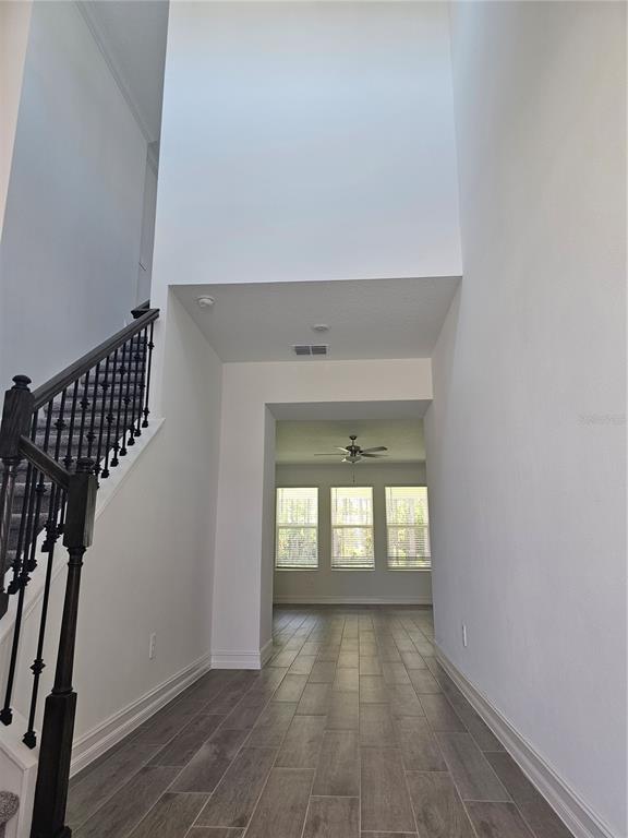 A high-ceilinged entryway features a staircase with dark railings and wood-look tile flooring — 18271 PEARL VIEW PLACE, LUTZ, FL