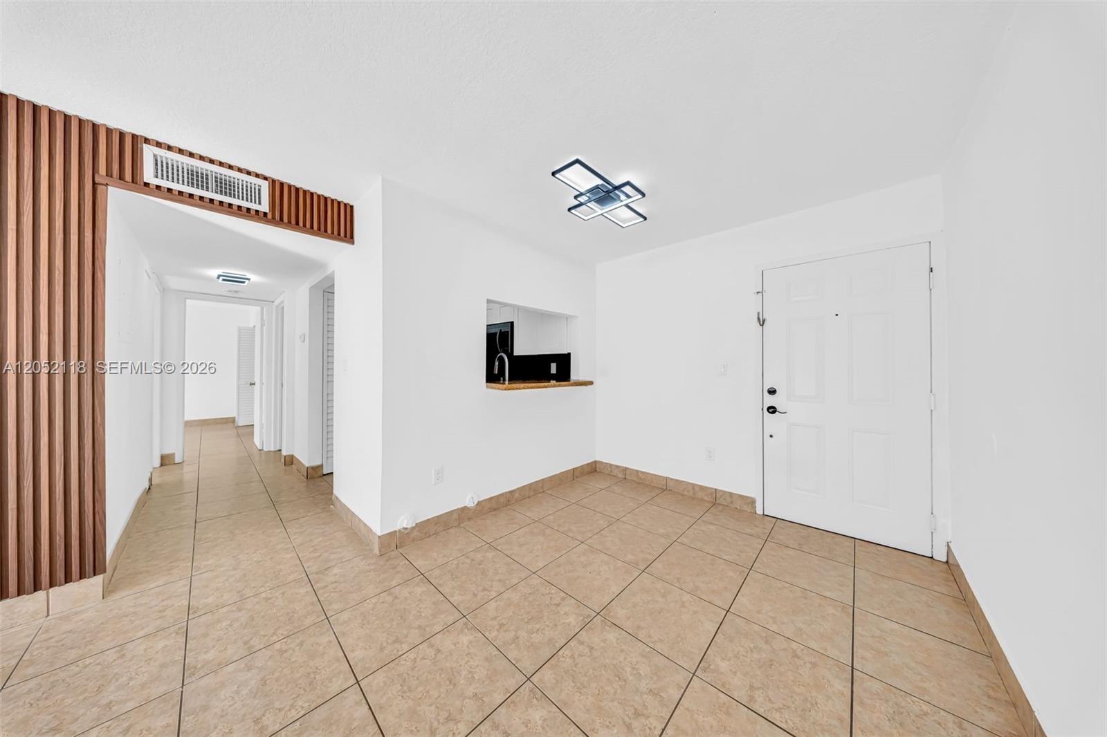An entryway with tile flooring leads to a hallway and a kitchen pass-through window — 8145 NW 7th St # 111, Miami FL 33126, MIAMI, FL