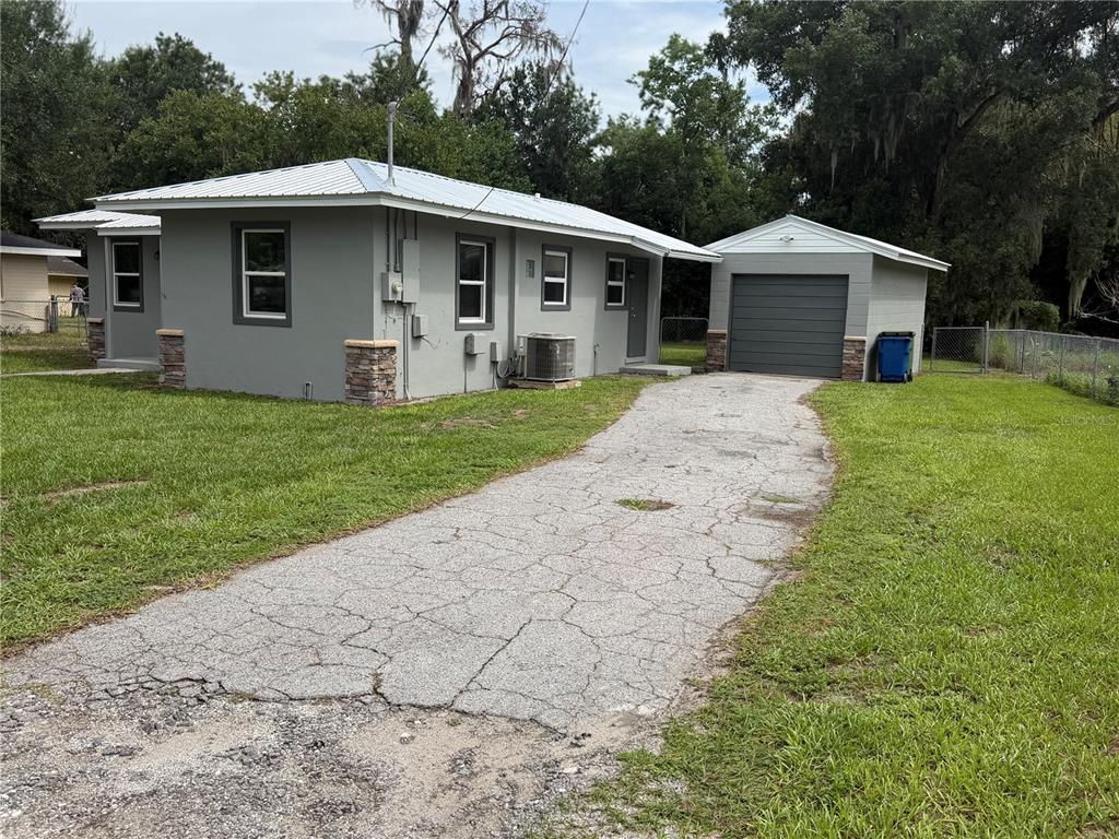 A gray house with a metal roof and a detached garage sits on a grassy lot — 1986 AVENUE F, WINTER HAVEN, FL