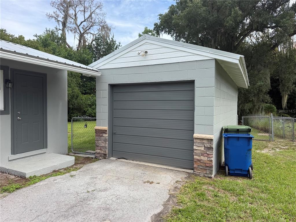 A detached concrete block garage with a gray roll-up door and stone accents — 1986 AVENUE F, WINTER HAVEN, FL