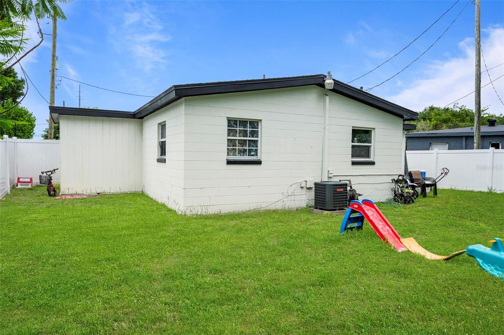 The exterior of a white concrete block house features a backyard with a children's slide — 4333 ARCH STREET, ORLANDO, FL