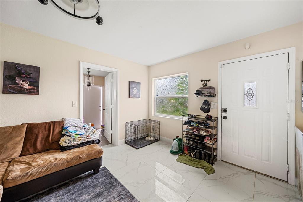 A living room with tile floors, a brown sofa, a dog crate, and a shoe rack — 4333 ARCH STREET, ORLANDO, FL