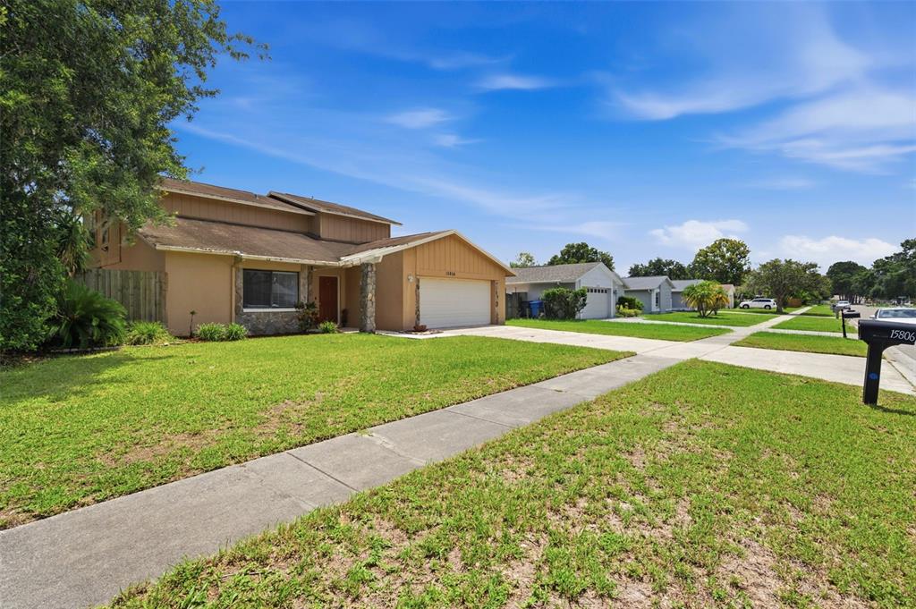 A two-story tan house with a stone accent wall and a two-car garage — 15806 PENNINGTON ROAD, TAMPA, FL