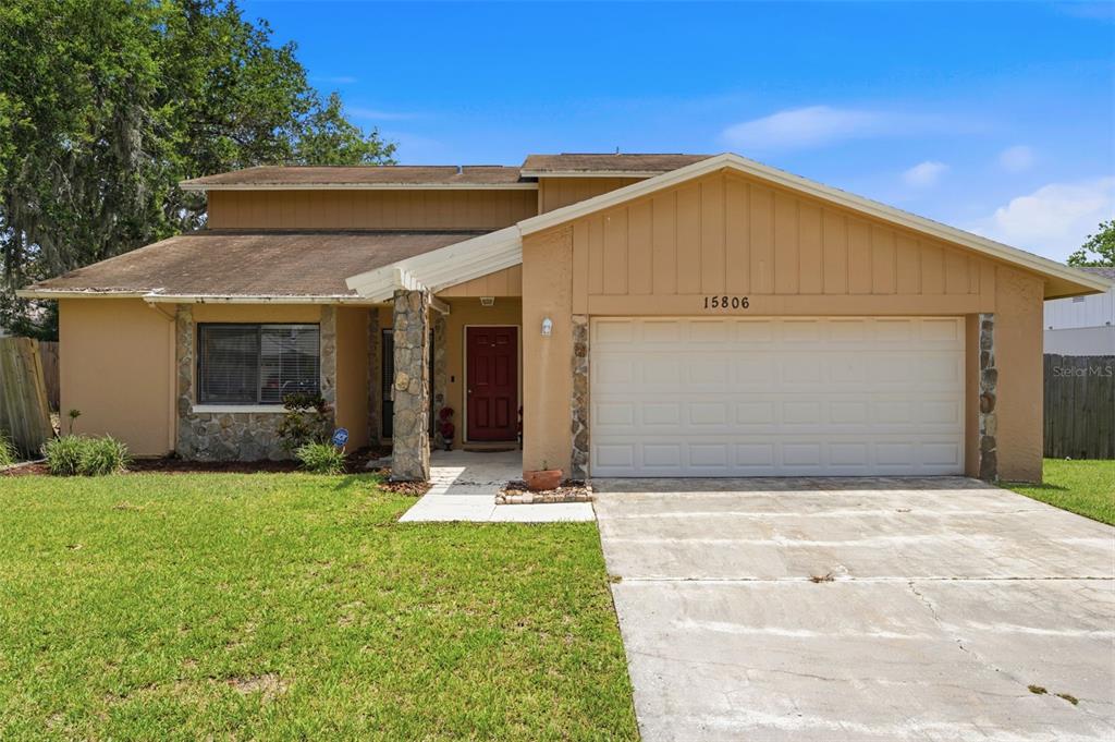 A two-story house with a tan exterior, stone accents, and a two-car garage — 15806 PENNINGTON ROAD, TAMPA, FL