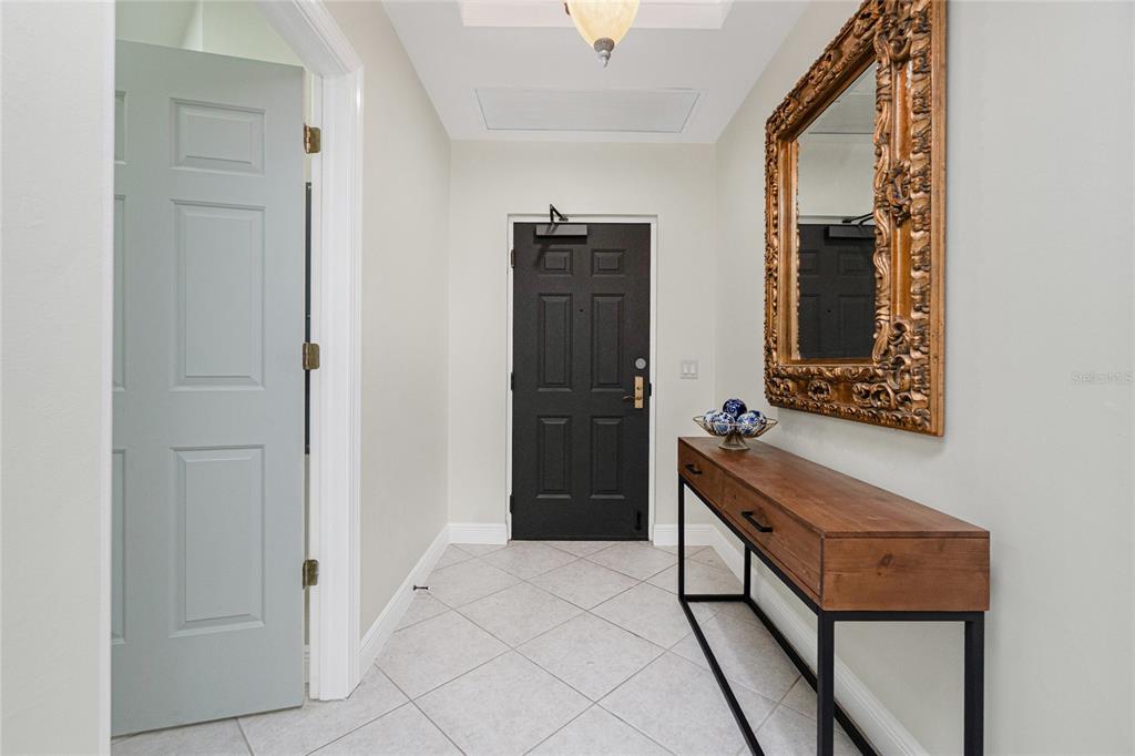 A foyer features a black door, a wooden console table, and a large ornate mirror — 3313 SUNSET KEY CIR UNIT 701, PUNTA GORDA, FL