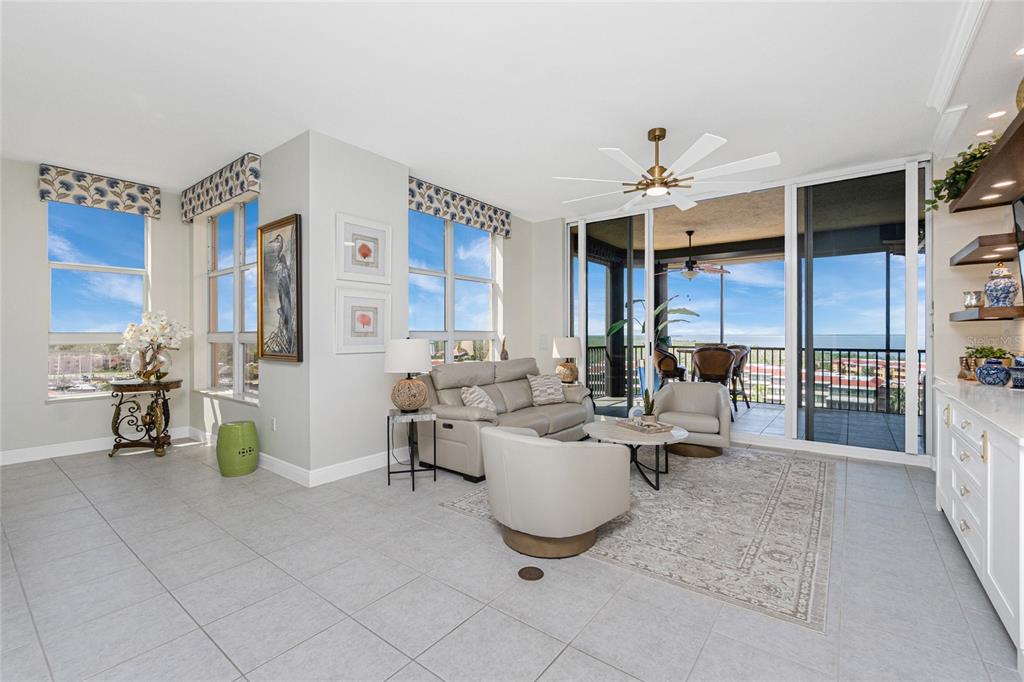 A bright living room features light tile floors, neutral furniture, and sliding doors to a balcony — 3313 SUNSET KEY CIR UNIT 701, PUNTA GORDA, FL