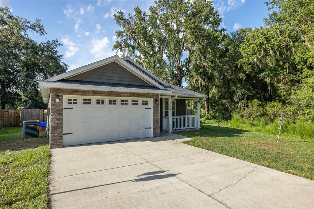 A single-story house with a stone-accented garage, concrete driveway, and a small front porch — 3602 NW 55TH LANE, GAINESVILLE, FL