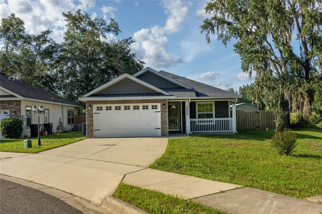 A single-story house with a white garage door, stone accents, and a front porch — 3602 NW 55TH LANE, GAINESVILLE, FL
