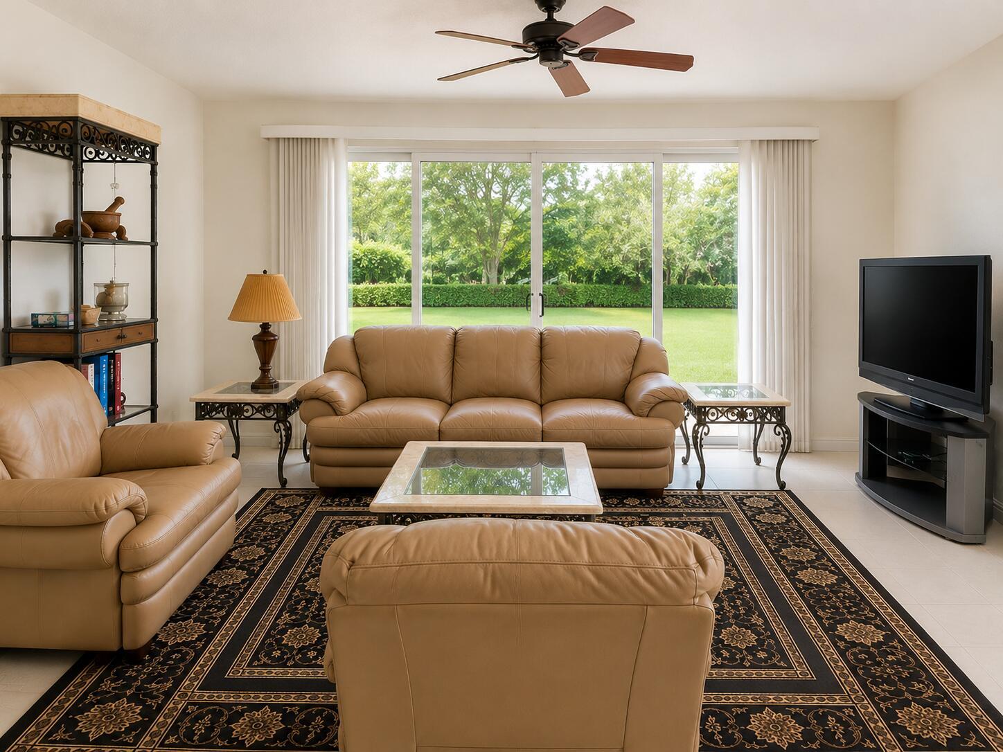 A living room features tan leather furniture, a patterned area rug, and sliding glass doors — 7775 YARDLEY Drive # 115, Tamarac FL 33321, TAMARAC, FL