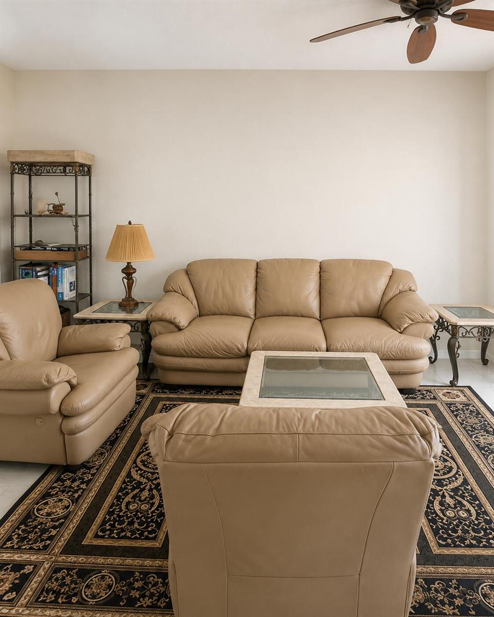 A living room features a tan leather sofa and armchairs arranged on a patterned rug — 7775 YARDLEY Drive # 115, Tamarac FL 33321, TAMARAC, FL