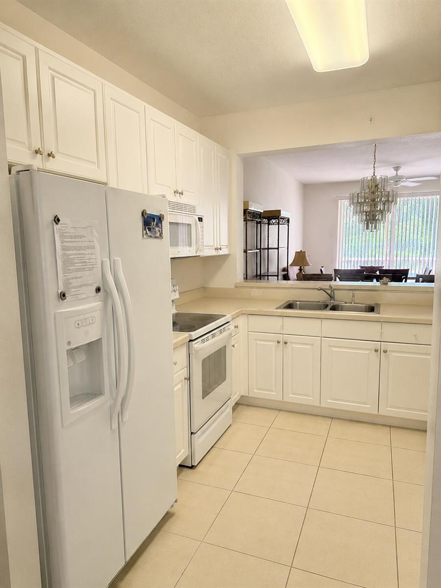 A kitchen with white cabinets, white appliances, and light-colored tile flooring — 7775 YARDLEY Drive # 115, Tamarac FL 33321, TAMARAC, FL