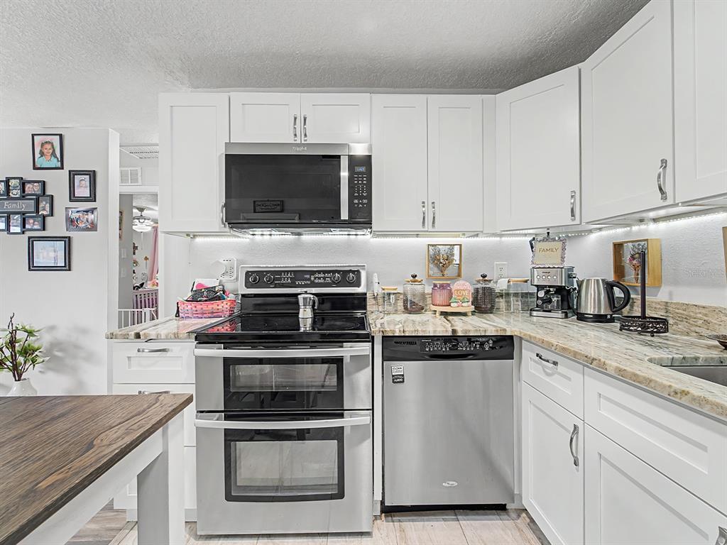 A kitchen features white cabinets, stainless steel appliances, and light-colored granite countertops — 197 ROSEDALE AVENUE, SPRING HILL, FL