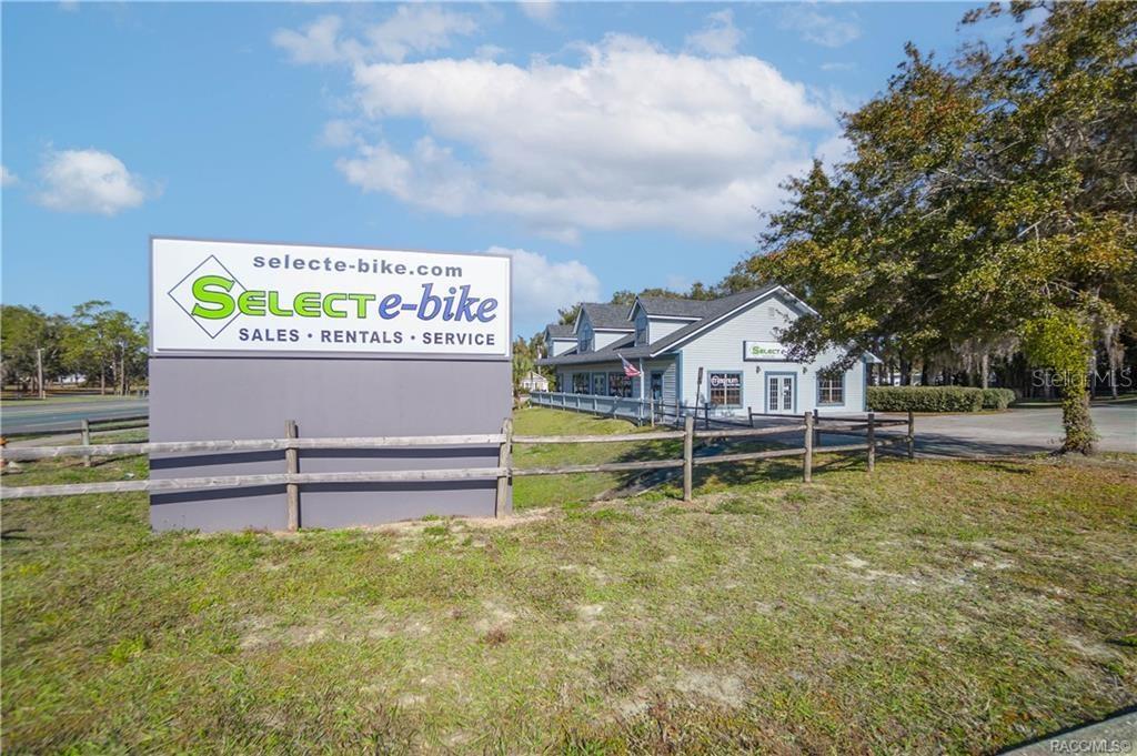 A large sign for an e-bike shop stands in front of a light blue building — 525 S US HIGHWAY 41, INVERNESS, FL