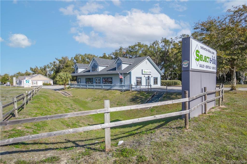 A light blue commercial building with a large sign stands behind a wooden fence — 525 S US HIGHWAY 41, INVERNESS, FL