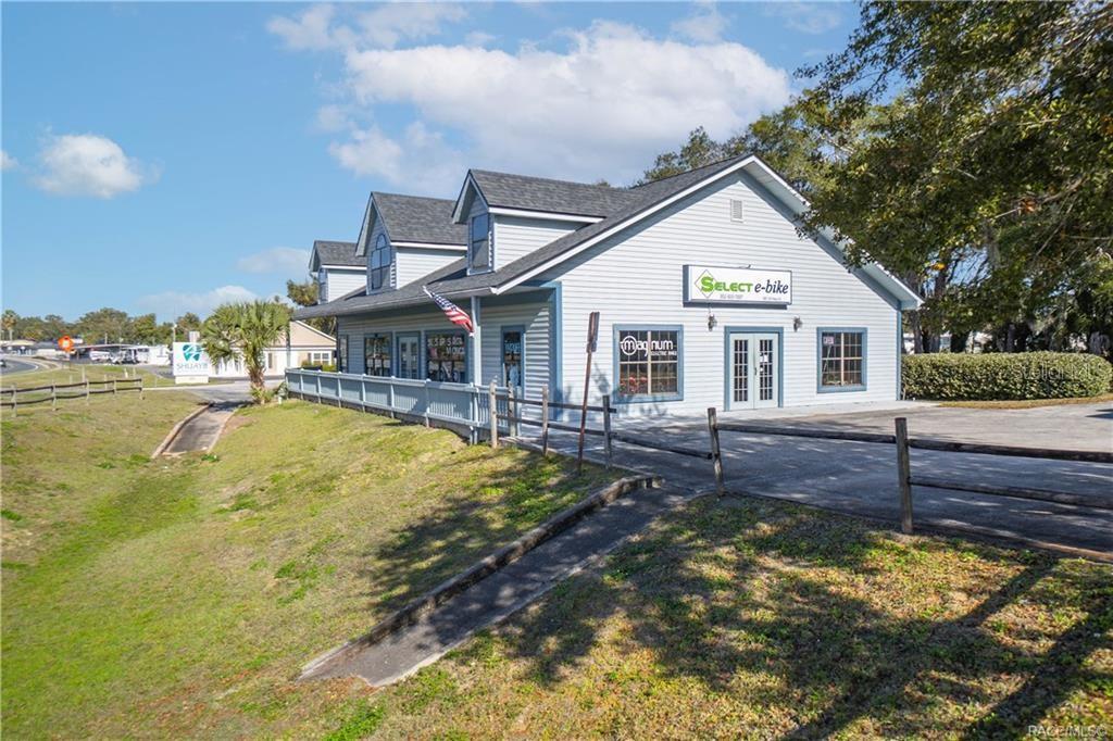 A light blue commercial building with a wrap-around porch sits on a grassy lot — 525 S US HIGHWAY 41, INVERNESS, FL