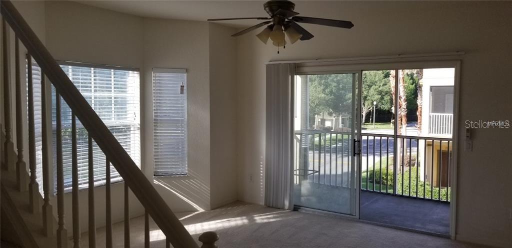 A living room features a staircase, a ceiling fan, and sliding glass doors to a balcony — 2532 GRAND CENTRAL PARKWAY UNIT 10, ORLANDO, FL