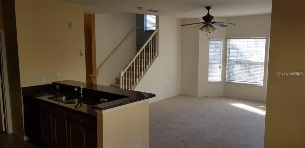 A kitchen with dark countertops overlooks a living area with carpet and a staircase — 2532 GRAND CENTRAL PARKWAY UNIT 10, ORLANDO, FL