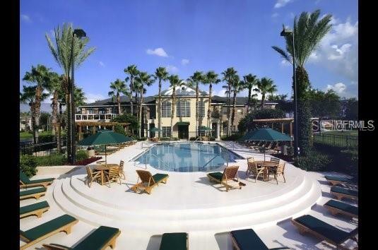 A swimming pool with lounge chairs and umbrellas sits in front of a large building — 2532 GRAND CENTRAL PARKWAY UNIT 10, ORLANDO, FL