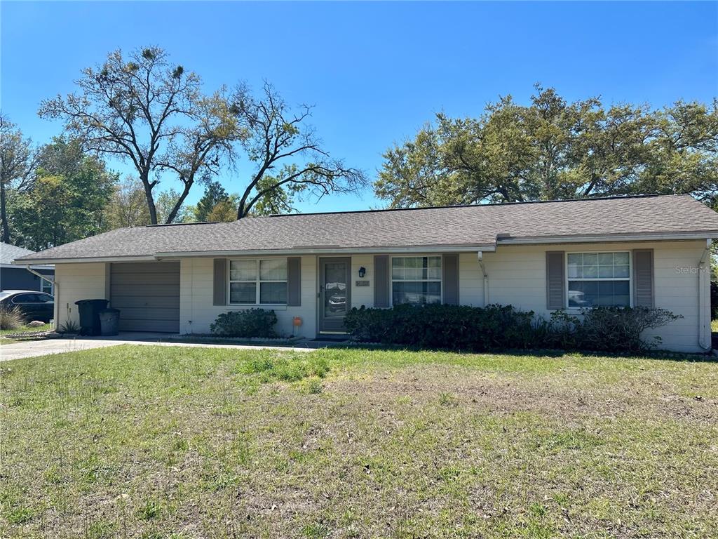 A single-story house with a beige exterior, a one-car garage, and a front lawn — 14152 SW 42ND TERRACE ROAD, OCALA, FL