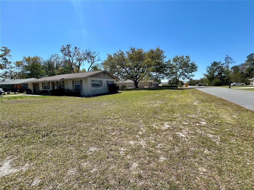 A single-story house sits on a large, grassy lot next to a paved road — 14152 SW 42ND TERRACE ROAD, OCALA, FL