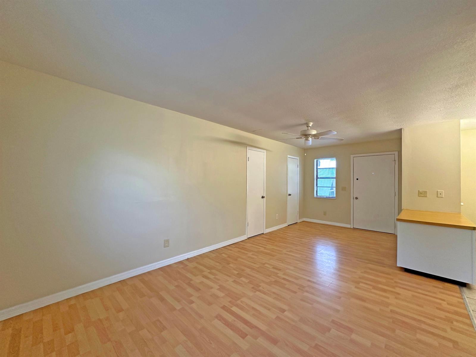 An empty room features light-colored walls, wood-look flooring, two interior doors, and a ceiling fan — 1021 SE Monterey Road # A22, Stuart FL 34994, STUART, FL
