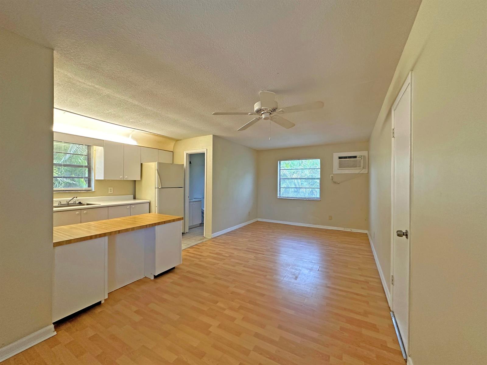 An open-concept kitchen and living area with light wood flooring, white cabinets, and a ceiling fan — 1021 SE Monterey Road # A22, Stuart FL 34994, STUART, FL