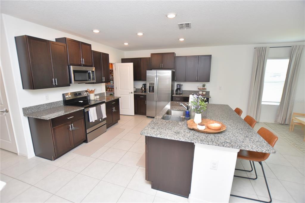 A kitchen with dark wood cabinets, granite countertops, stainless steel appliances, and a central island — 2767 RED EGRET DRIVE, BARTOW, FL