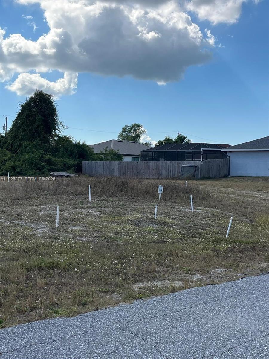 A vacant, grassy lot features several white survey stakes marking the property boundaries — 2002 NW 3 TER, Cape Coral FL 33993, CAPE CORAL, FL