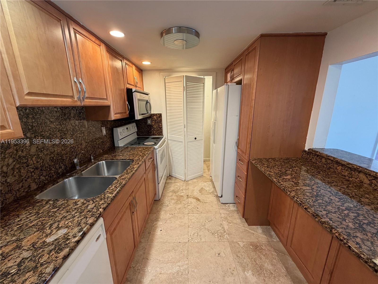 A galley kitchen features wood cabinets, granite countertops, stainless steel appliances, and tile flooring — 240 Lakeview Dr # 308, Weston FL 33326, WESTON, FL