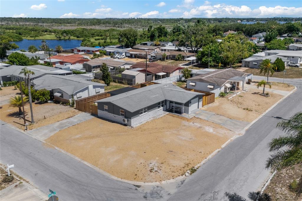 An aerial view shows a gray single-story house on a corner lot with sparse landscaping — 1118 EXCALIBUR STREET, HOLIDAY, FL