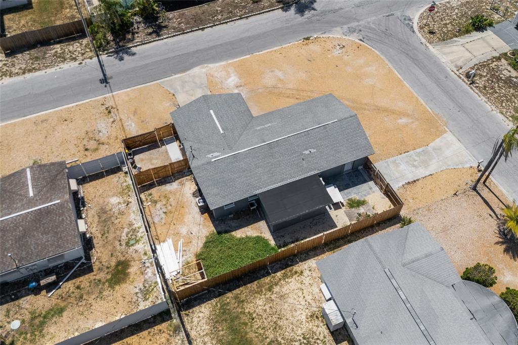 An aerial view shows a single-story house with a gray roof and a fenced backyard — 1118 EXCALIBUR STREET, HOLIDAY, FL