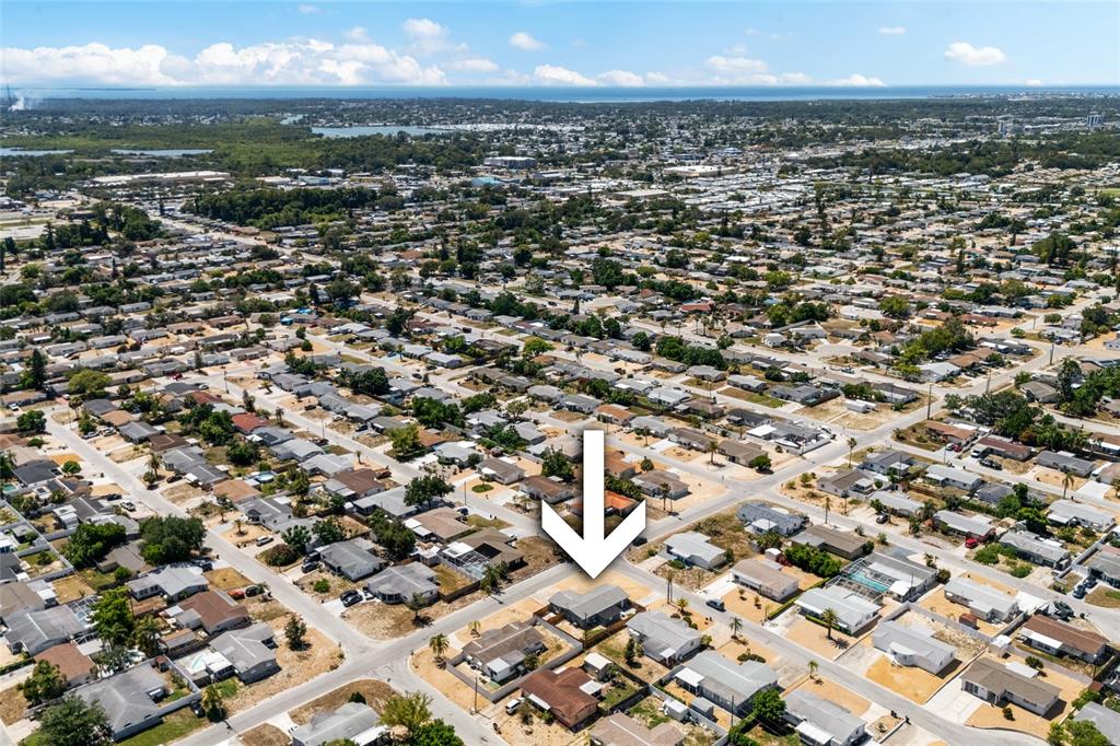 An aerial view shows a residential neighborhood with a white arrow pointing to a house — 1118 EXCALIBUR STREET, HOLIDAY, FL