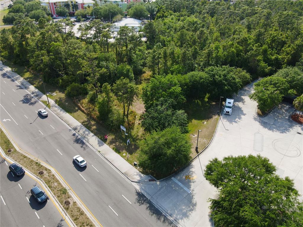 An aerial view shows a vacant, wooded lot situated between a multi-lane road and parking — 11914 INTERNATIONAL DRIVE, ORLANDO, FL