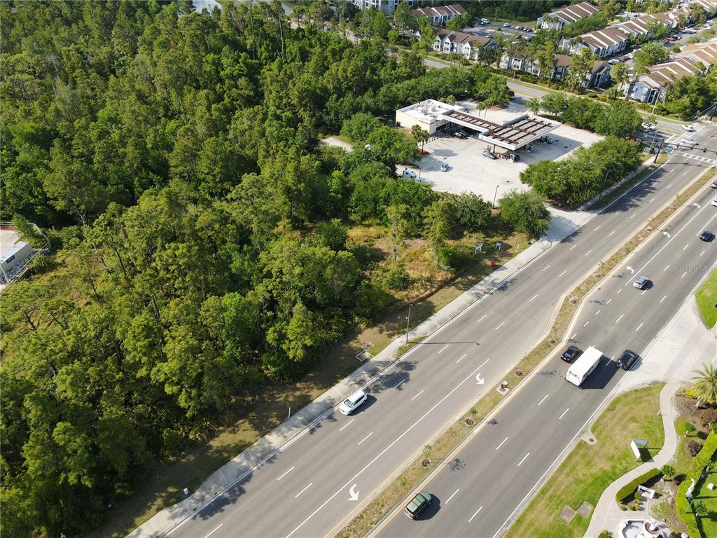 An aerial view shows a wooded lot adjacent to a gas station and a multi-lane road — 11914 INTERNATIONAL DRIVE, ORLANDO, FL