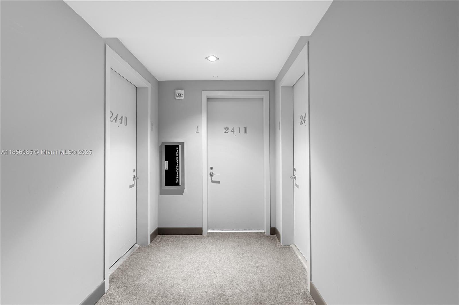 A hallway features gray carpet, light-colored walls, and three doors labeled 2410, 2411, and 2412 — 1300 S Miami Ave # 2411, Miami FL 33130, MIAMI, FL